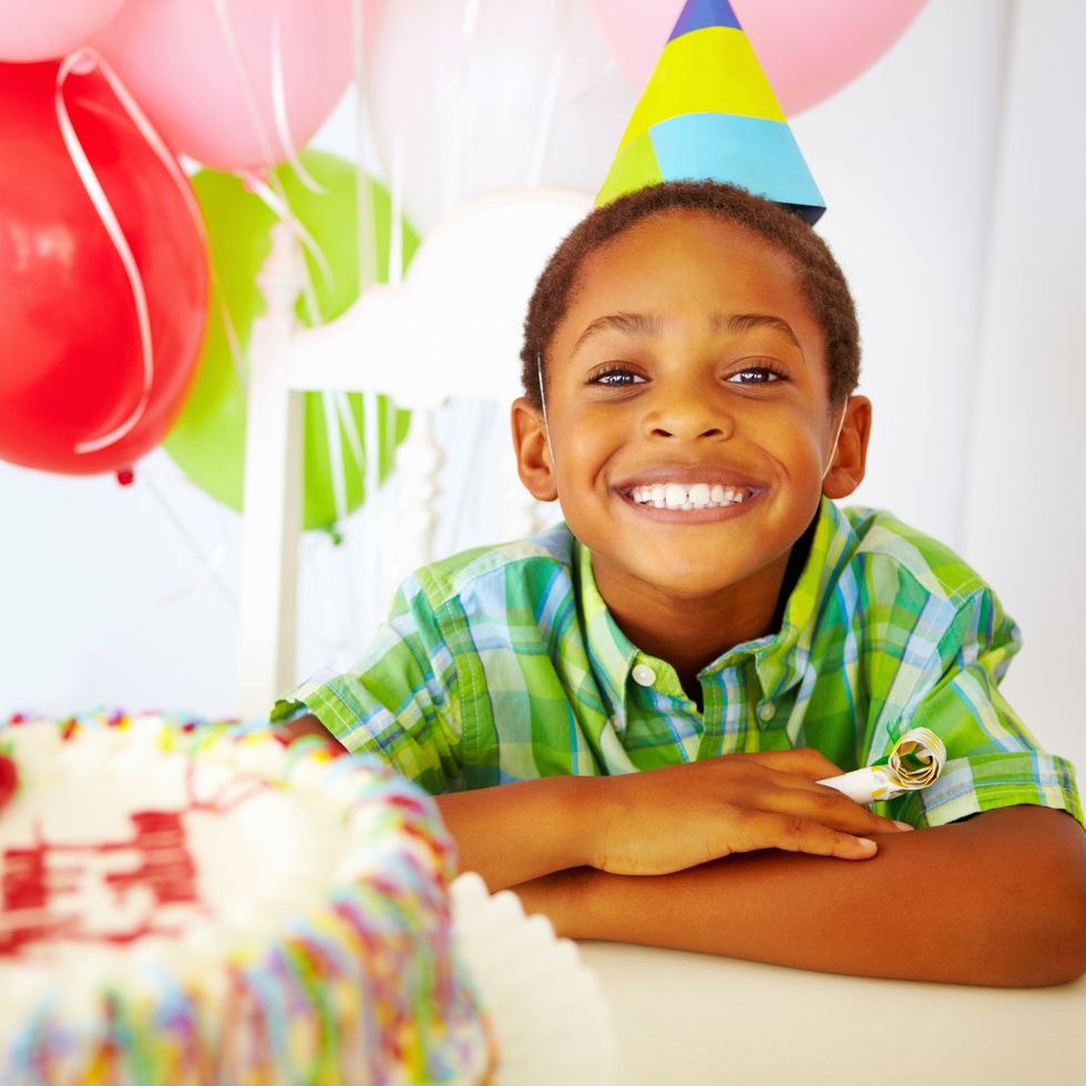 smiling little boy in front of cake at birthday party