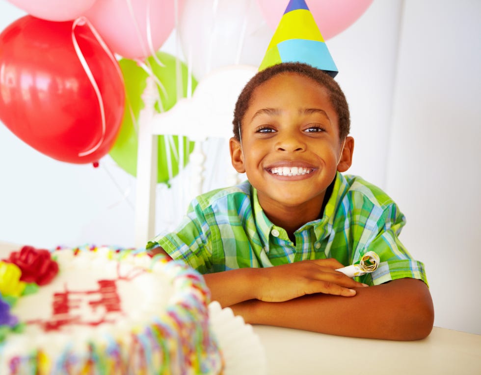 smiling little boy in front of cake at birthday party