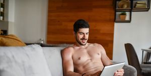 smiling male in underwear relaxing at home and using digital tablet