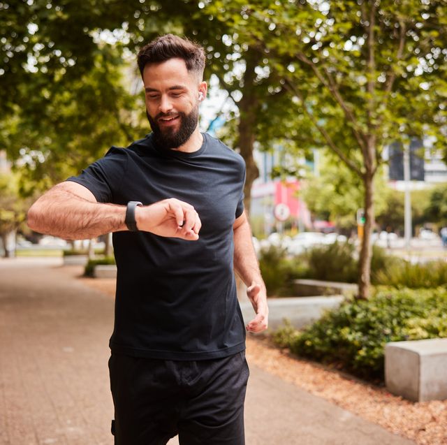 smiling man checking his fitness tracker during a park run