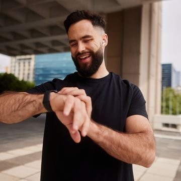 smiling man checking his fitness tracker during a city run