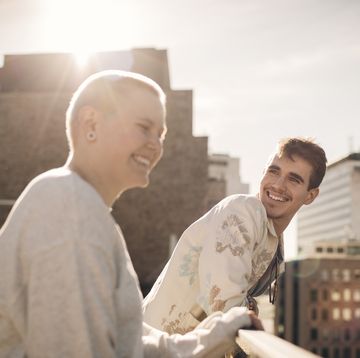 smiling man looking at transgender friend on sunny day