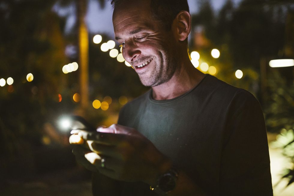 smiling man texting during sunset
