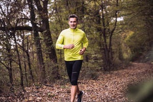 smiling mature man jogging in forest