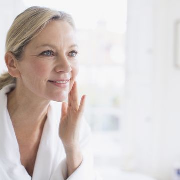 mujer echandose crema feliz y sonriente