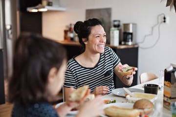 smiling mother sitting with daughter while having breakfast at dining table