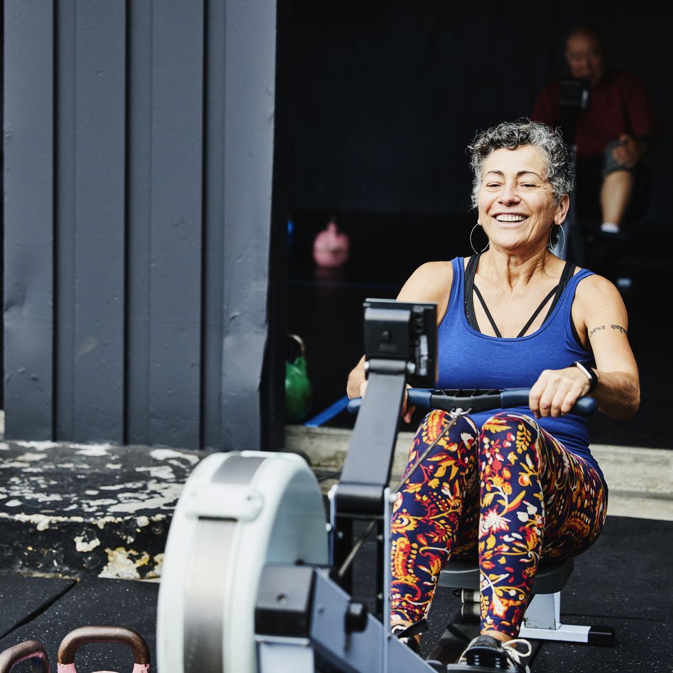 smiling senior woman working out on rowing machine at outdoor gym