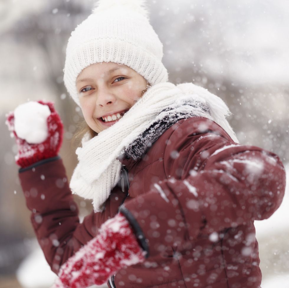 smiling teenage girl throwing snowball