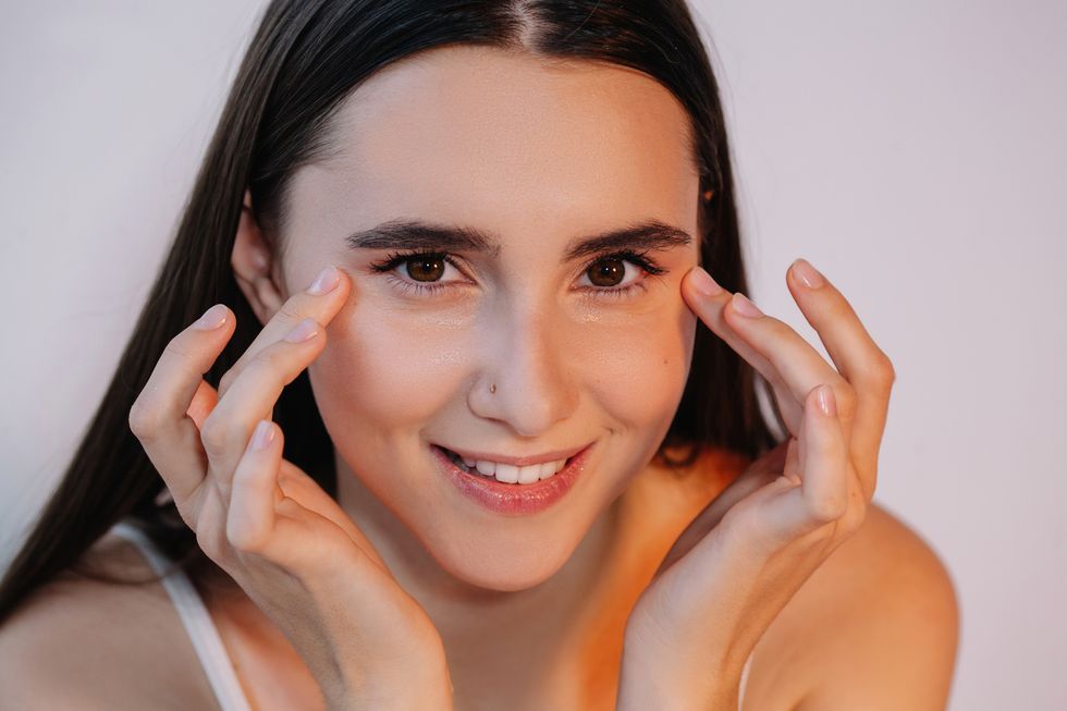 smiling woman applying eye cream