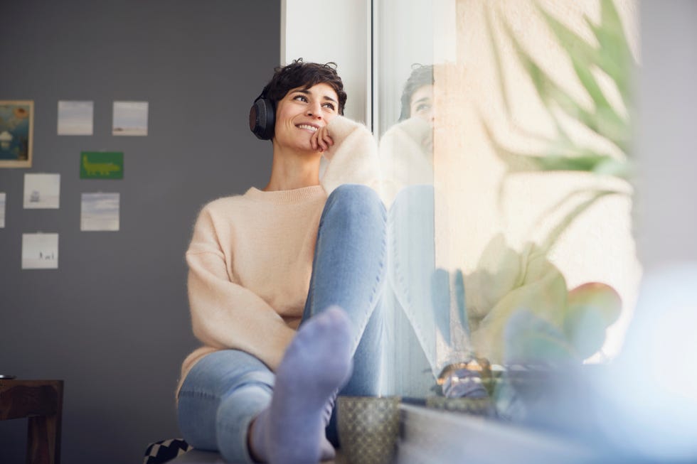 long distance valentines day - Smiling woman at home wearing headphones  sitting at the window