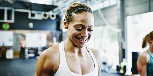 Smiling woman carrying kettlebells during workout