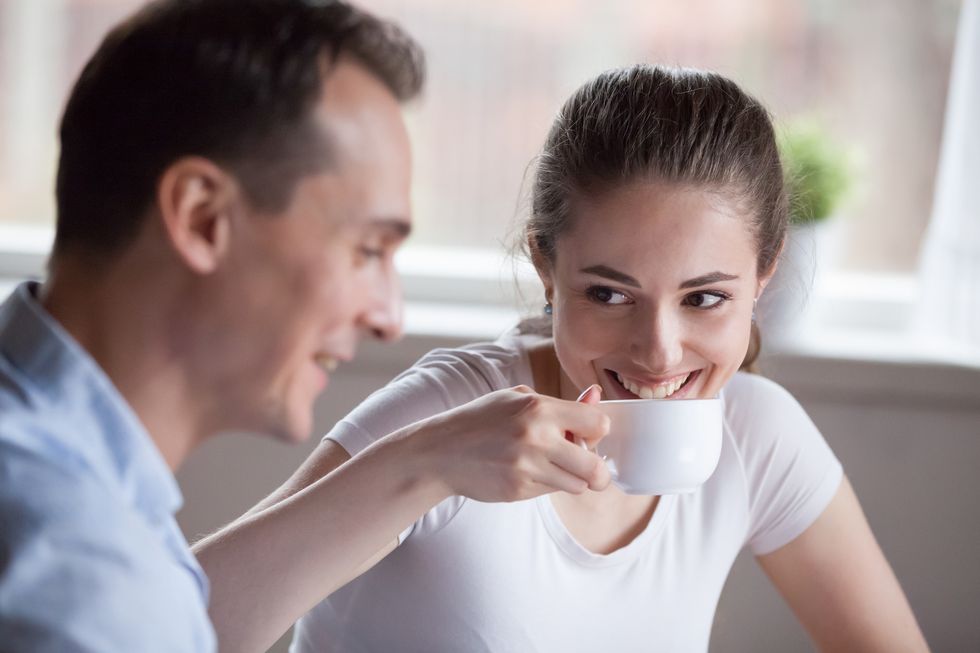 Smiling woman drinking coffee talking with handsome man