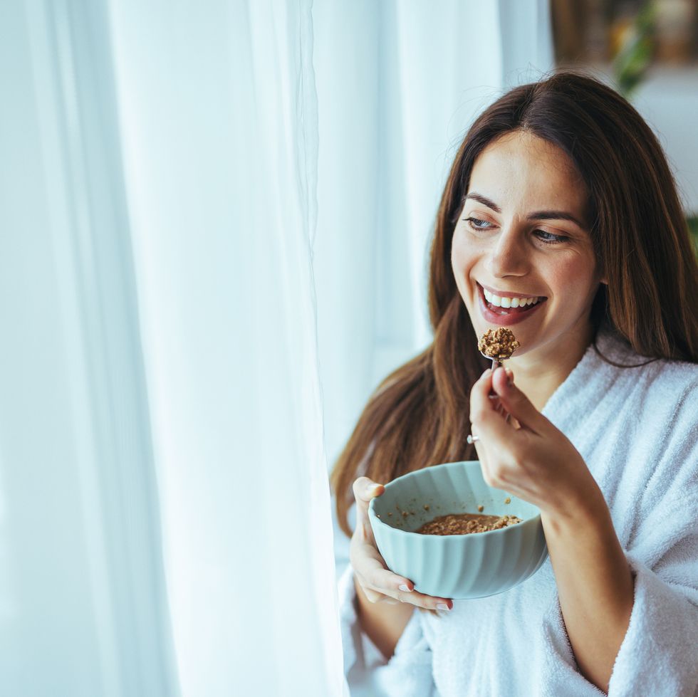 smiling woman enjoys breakfast in cozy morning light at home