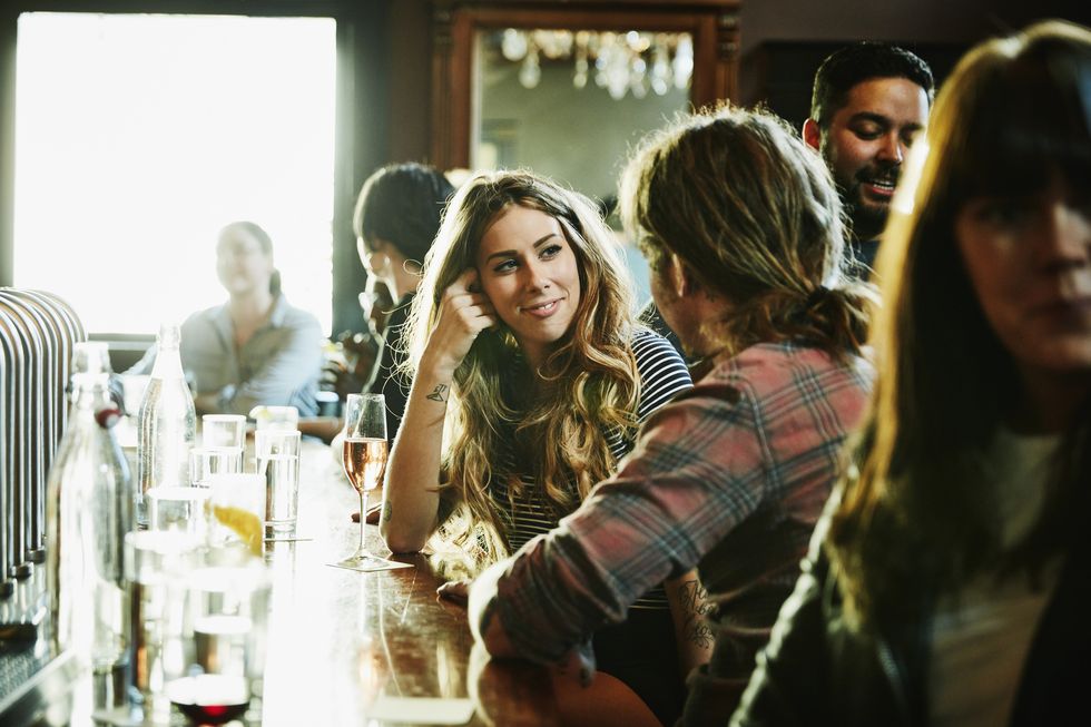 Smiling woman flirting with man while sitting in bar