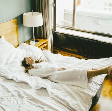 Smiling woman in bathrobe having fun on bed at hotel room
