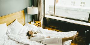 Smiling woman in bathrobe having fun on bed at hotel room