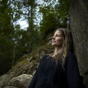 Smiling woman leaning against a rock in nature