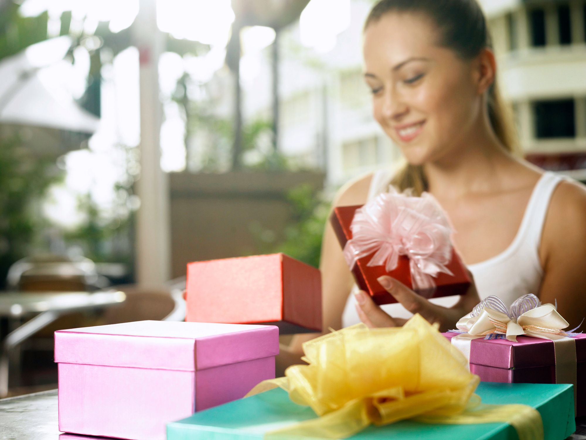 https://hips.hearstapps.com/hmg-prod/images/smiling-woman-looking-at-gifts-in-restaurant-royalty-free-image-1672663531.jpg