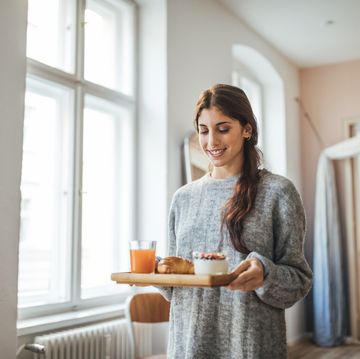 Smiling woman serving healthy breakfast in tray