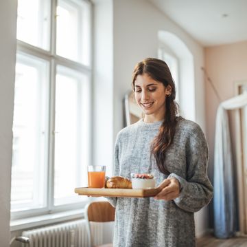 smiling woman serving healthy breakfast in tray