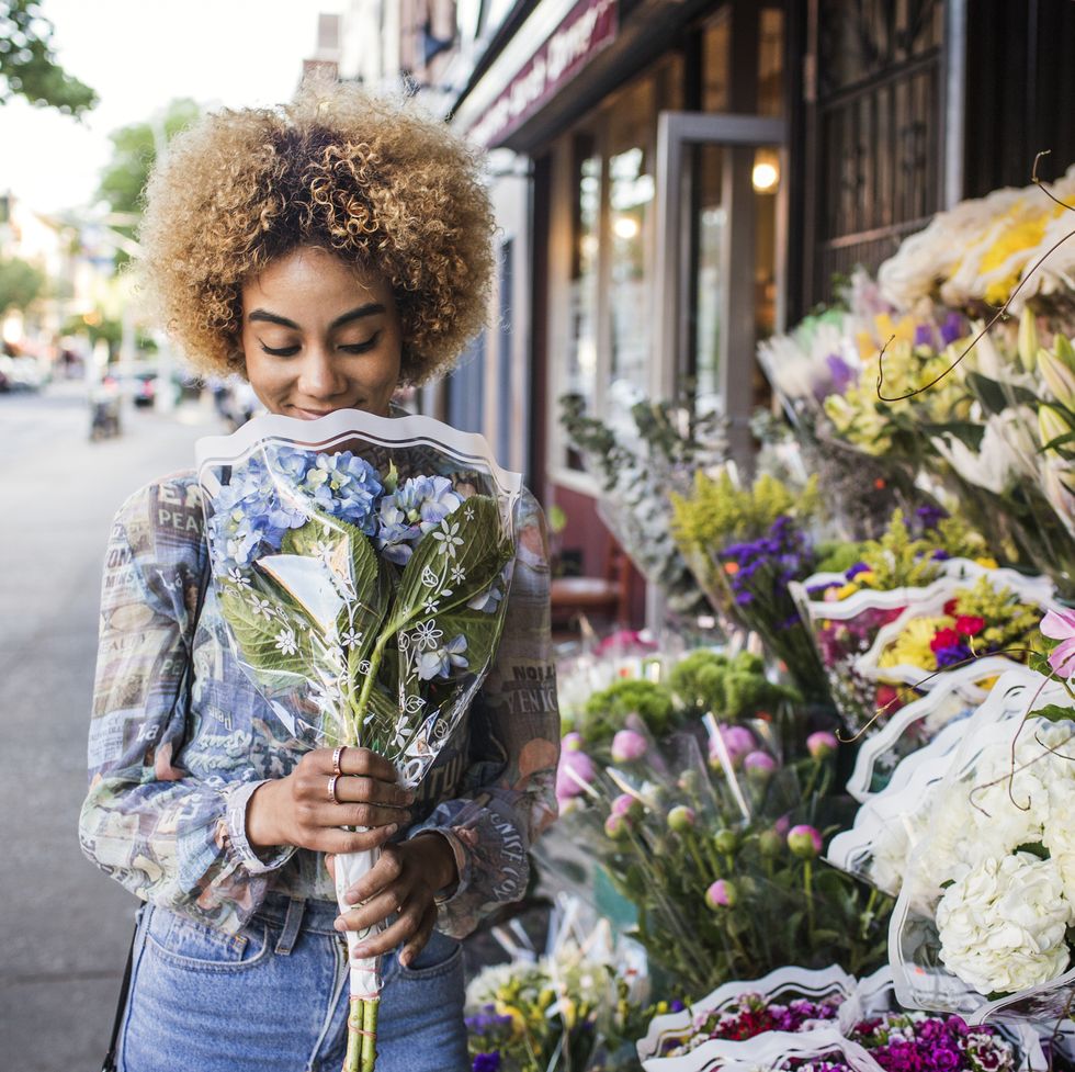 smiling woman smelling hydrangeas outside flower shop