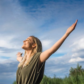 Una mujer sonríe mientras abre los brazos mirando al cielo una mujer sonríe mientras abre los brazos mirando al cielo