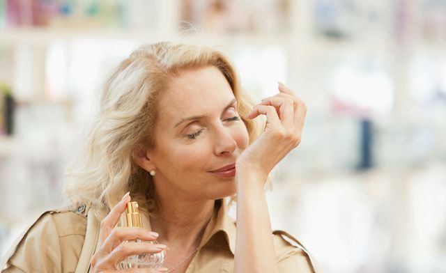 smiling woman testing perfume in store