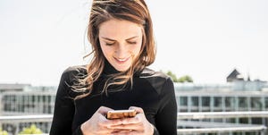 Smiling woman text messaging on roof terrace