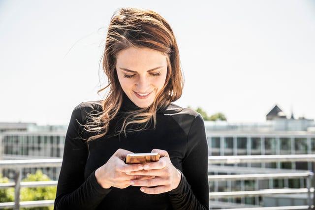 Smiling woman text messaging on roof terrace