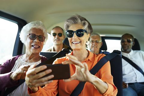 smiling woman using smart phone by friend in car