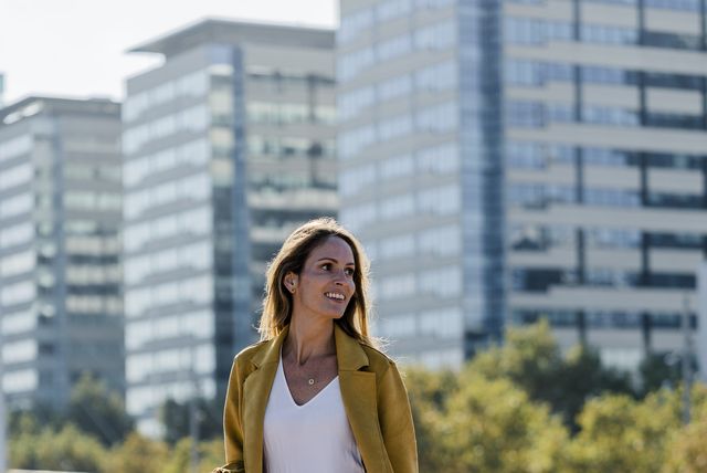 smiling woman with cell phone and handbag in the city on the go