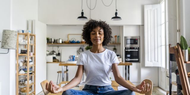 Smiling woman with closed eyes in yoga pose on table at home