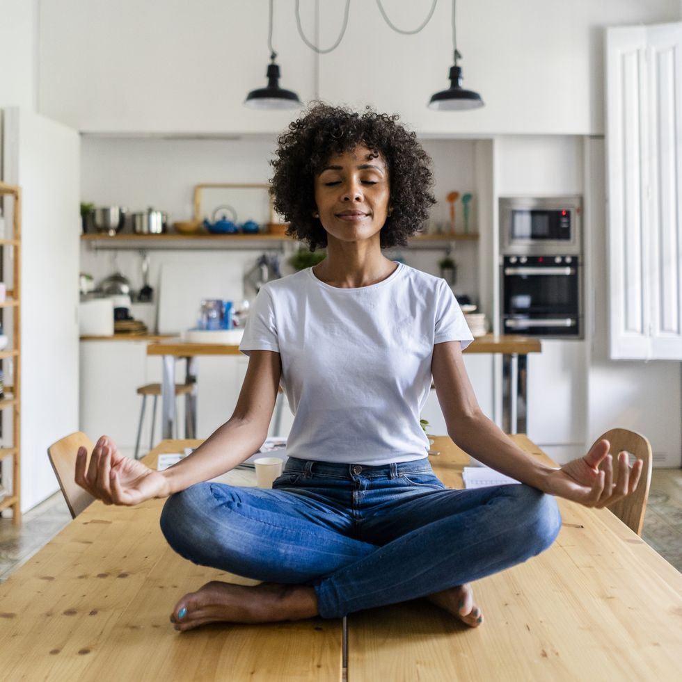 smiling woman with closed eyes in yoga pose on table at home