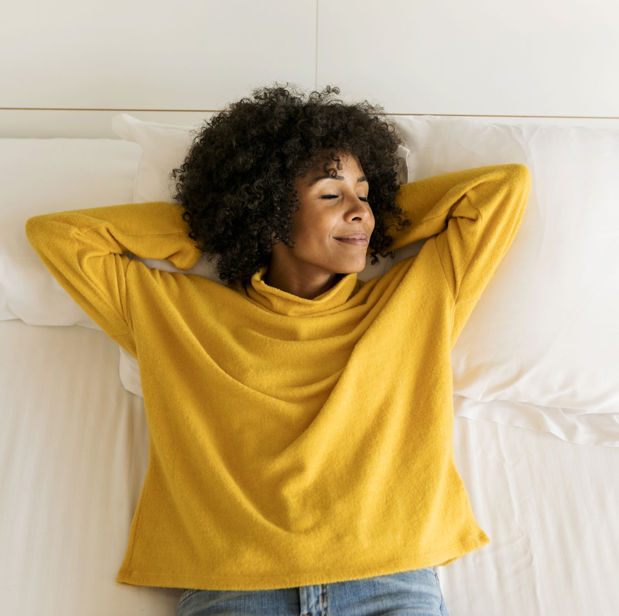 Smiling woman with closed eyes lying on bed