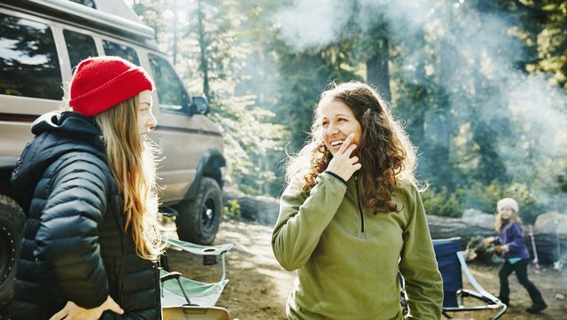 Smiling women in discussion while camping in woods