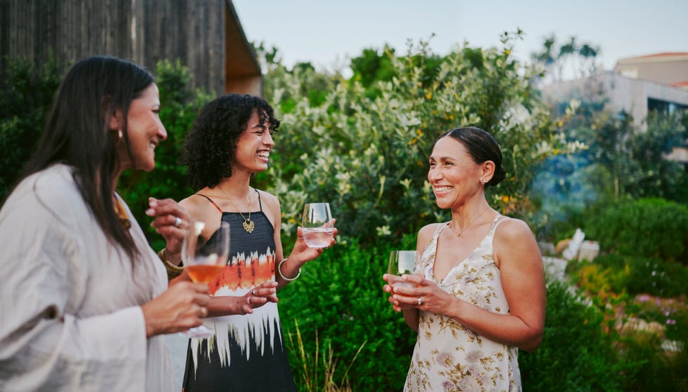 smiling women talking over drinks during an evening garden party