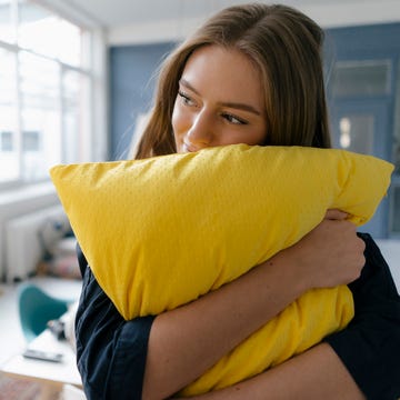Smiling young businesswoman with yellow pillow in office