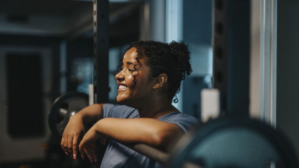ragazza in palestra sorridente appoggiata ad un bilancere