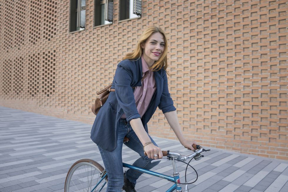 Smiling young woman riding bicycle in the city