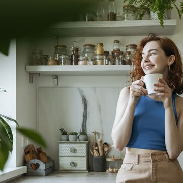 smiling young woman standing with coffee cup at home