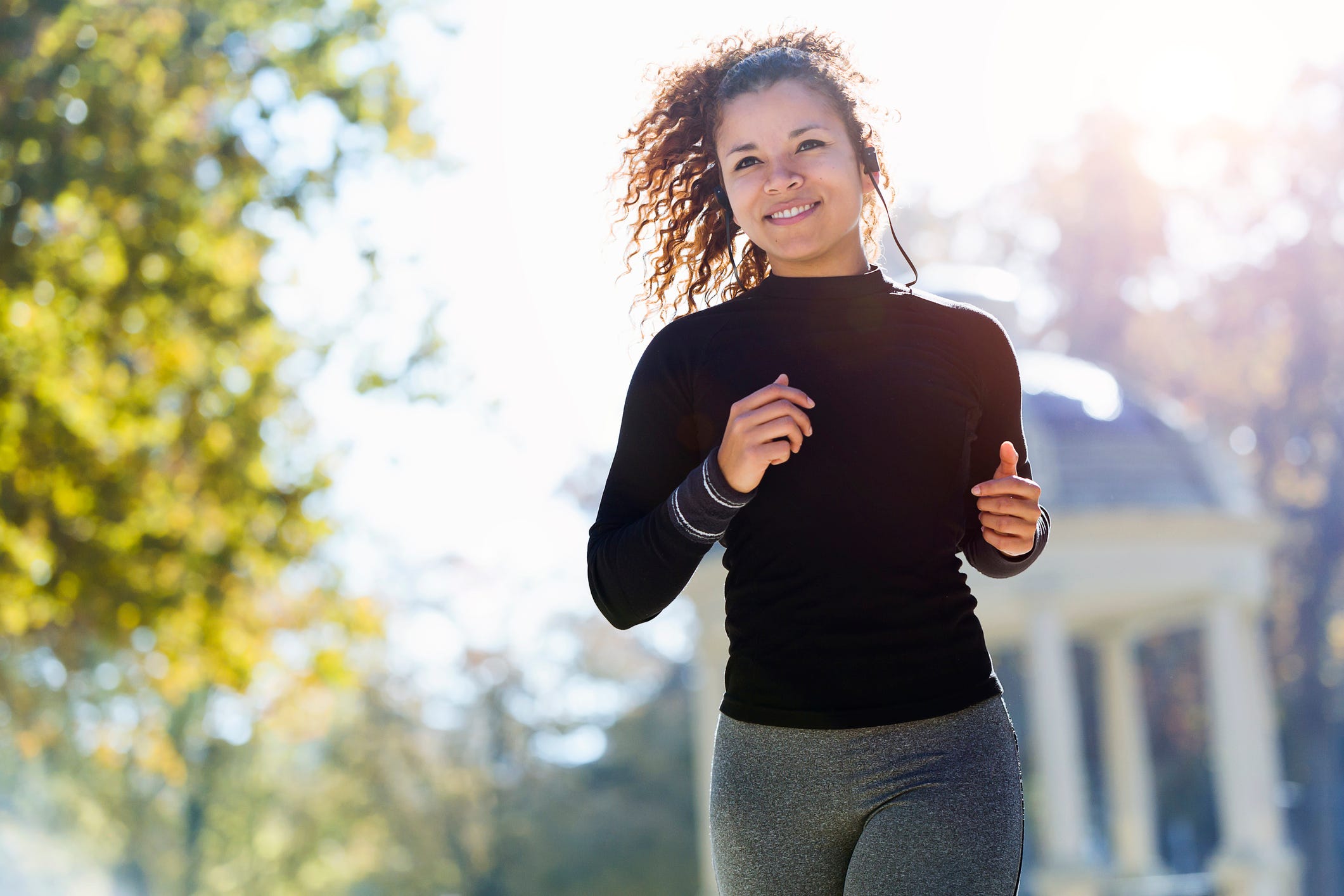 Smiling young woman with earphones running in park