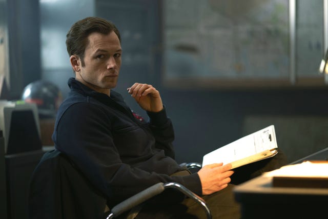 A person sitting in a chair holding a clipboard in an office environment
