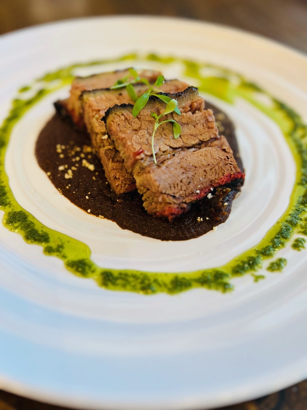 plate of sliced beef brisket accompanied by sauces