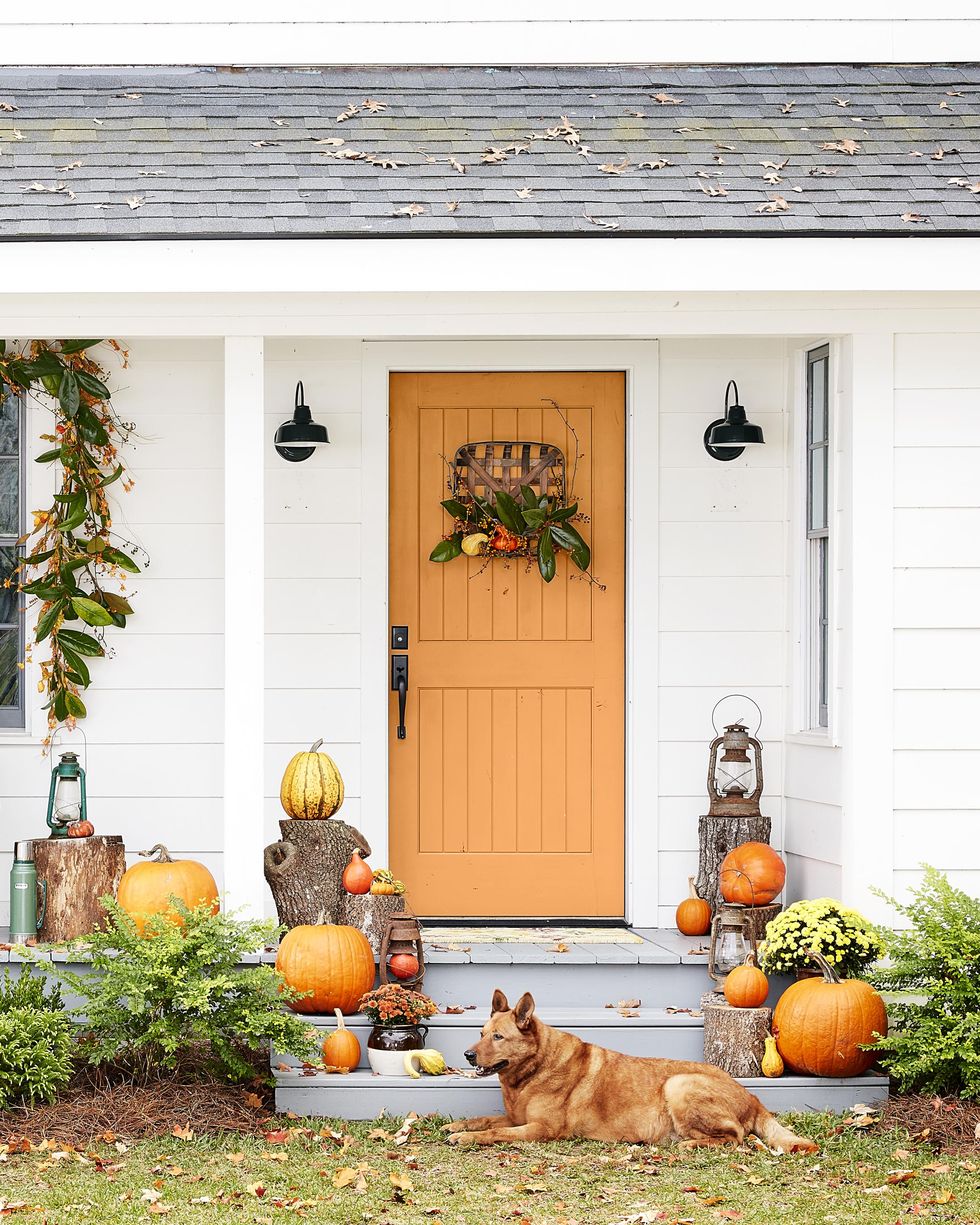 fall decorated porch with a magnolia garland over the window and a tobacco basket  wreath on the door