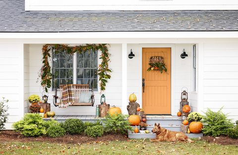 fall decorated porch with a magnolia garland over the window and a tobacco basket  wreath on the door