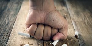 Cropped Hand Of Man Hitting Cigarette On Wooden Table