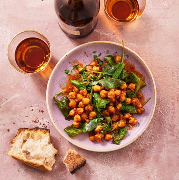 smoky glazed chickpeas and greens in a bowl with glasses of wine and torn baguette