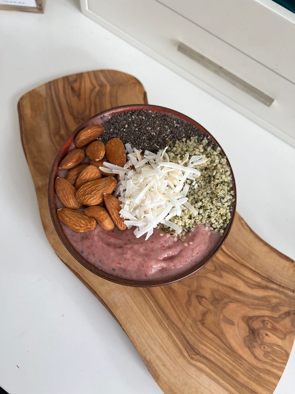 a strawberry smoothie bowl featuring protein powder, almonds, chia seeds, hemp hearts, and coconut for a total of 40 grams protein