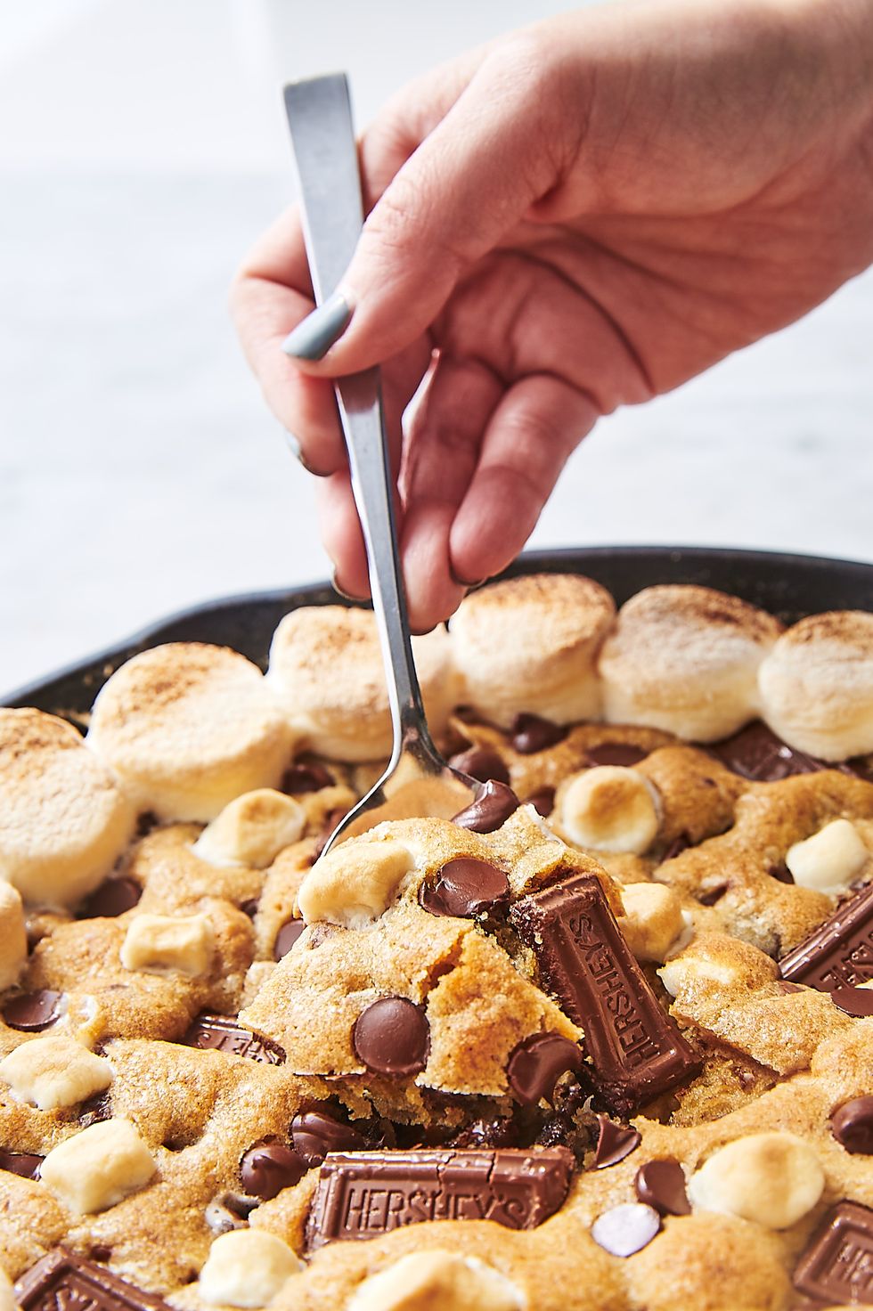 s'mores skillet cookie topped with chocolate chips, toasted marshmallows, mini hershey bars, and mini marshmallows