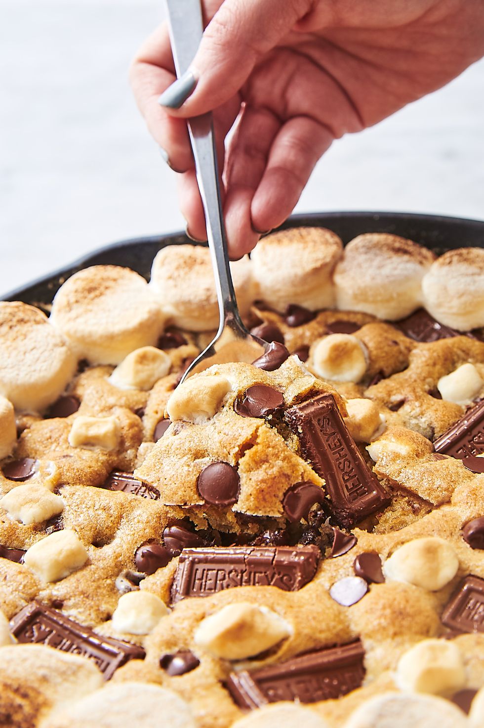 s'mores skillet cookie topped with chocolate chips, toasted marshmallows, mini hershey bars, and mini marshmallows